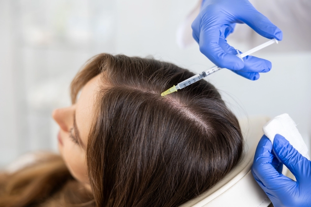 Provider in blue gloves administering PRP or PRF injection into patient's scalp for hair loss treatment
